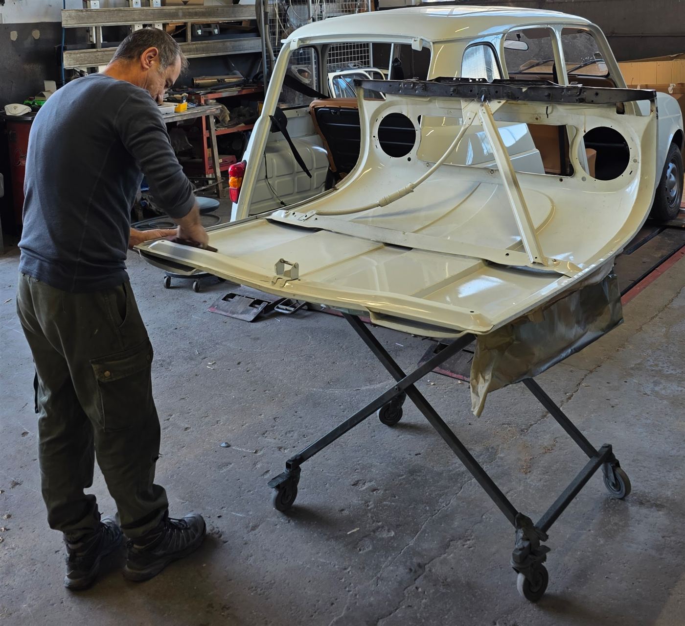 Ponçage du capot d'une Renault 4L en restauration dans l'atelier